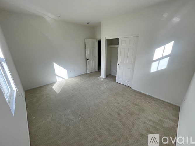 A room with carpeted floor and two white doors.