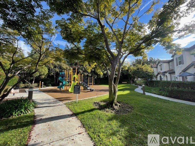 A playground with a slide and a tree in the foreground.