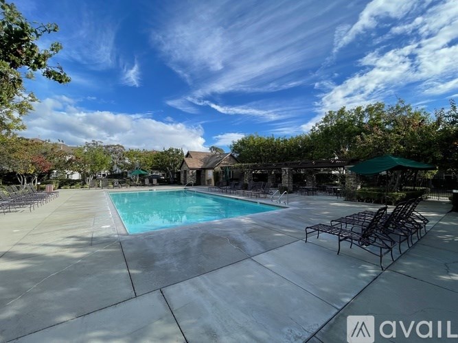 A large outdoor swimming pool surrounded by trees and lounge chairs.