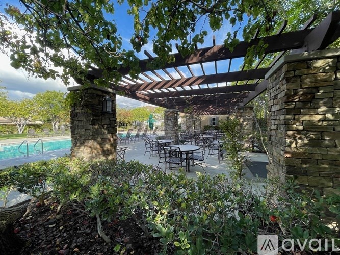 A patio area with tables and chairs under a pergola.