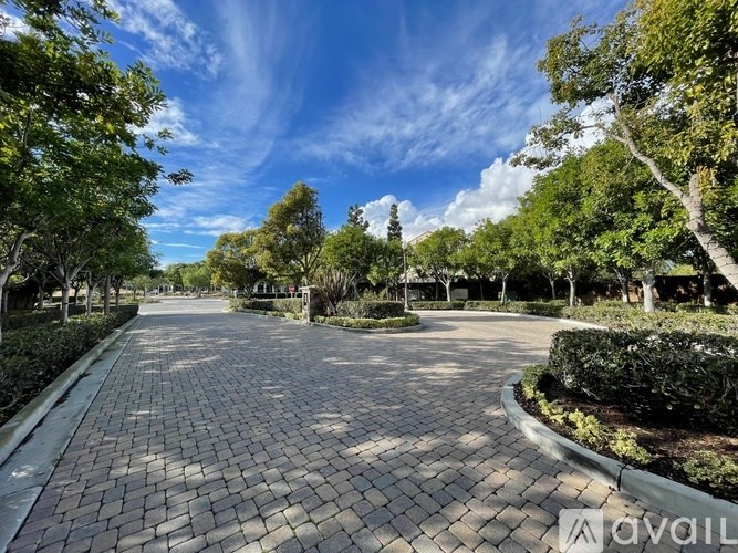 A tree-lined brick pathway leads through a park.