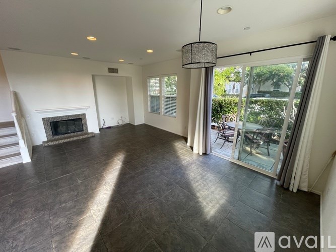 A spacious living room with a fireplace and sliding glass doors leading to a patio.