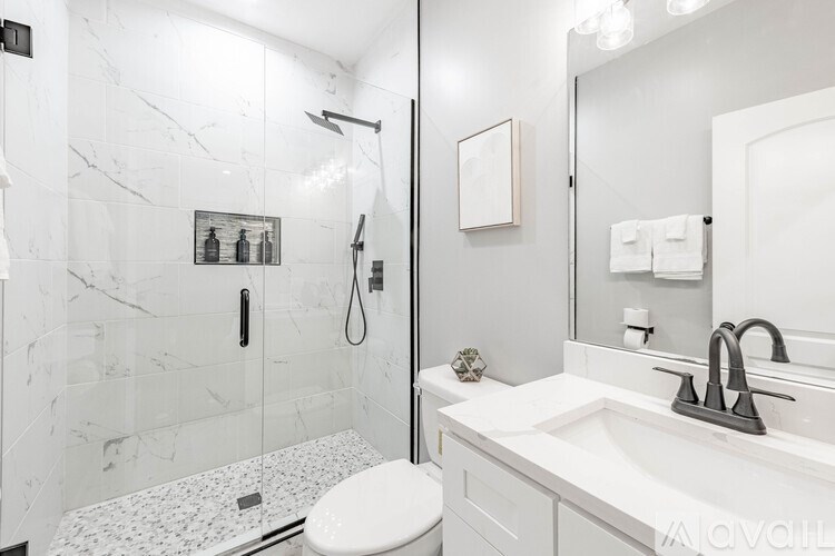 A bathroom with a marble tile shower and a white toilet.