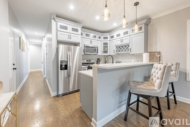 A kitchen with a white chair and a white fridge.
