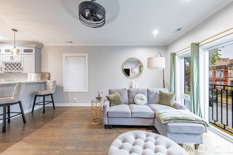 A modern living room with a grey sofa and a round ottoman.