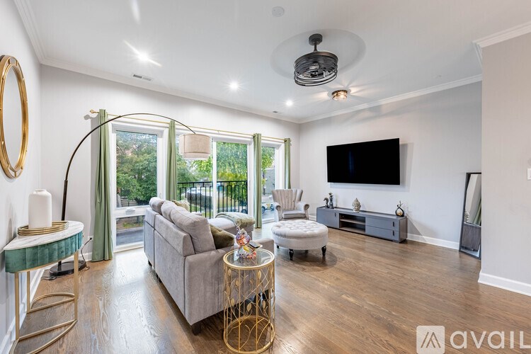 A living room with a grey couch, a TV, and a glass table with a gold frame.