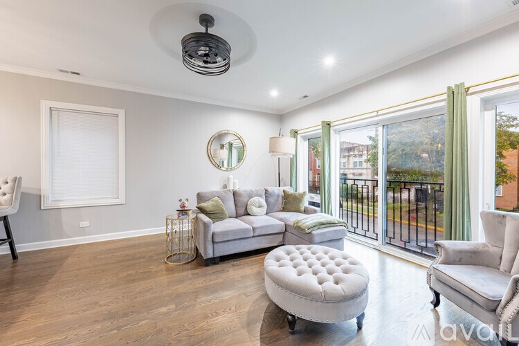A well-lit living room with a grey sofa, ottoman, and a white chair.