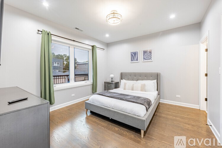 A bedroom with a large bed and a window with green curtains.