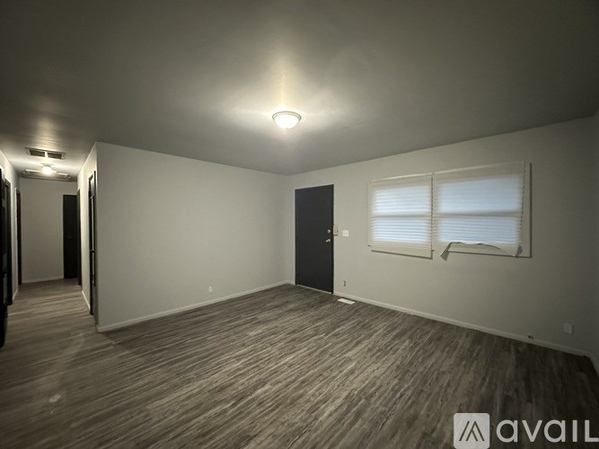 A room with wooden flooring and a window with blinds.