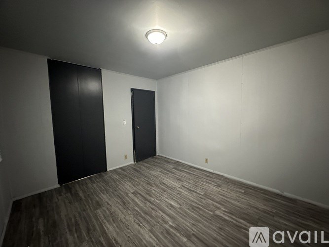 A room with a wooden floor and two black doors.