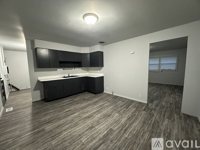 A modern kitchen with black cabinets and a wooden floor.