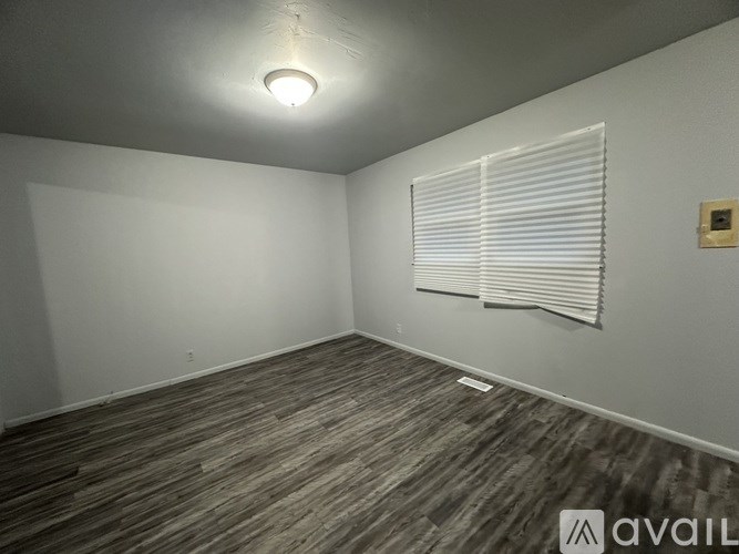 A room with wooden flooring and a window with blinds.
