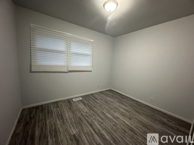 A room with wooden flooring and white walls.