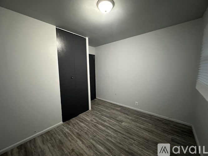 A room with a black door and wooden flooring.
