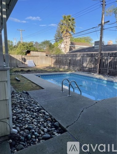 A pool surrounded by a rocky area and a wooden fence.