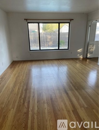 A room with wooden flooring and a large window.