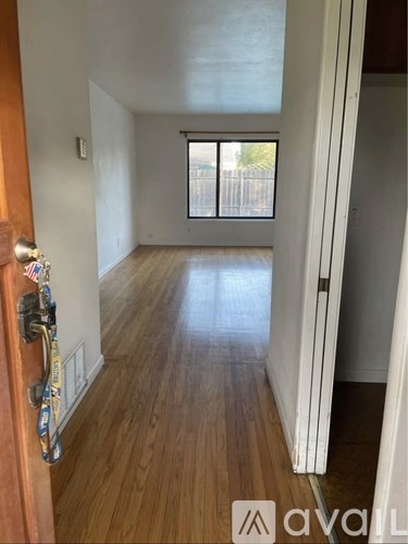 A hallway with wooden floors and a door on the left.