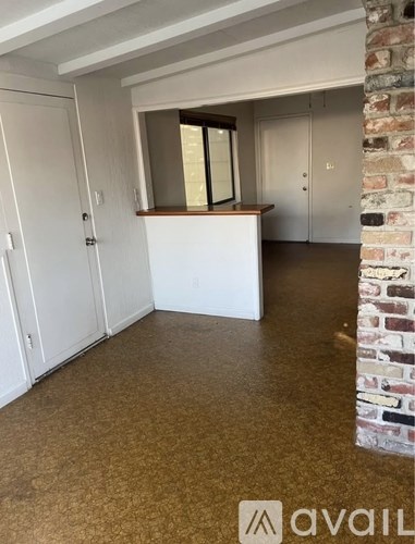 A room with a brown carpet and a brick wall.