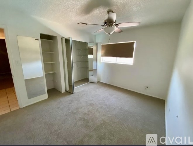 A room with a ceiling fan and a window with blinds.