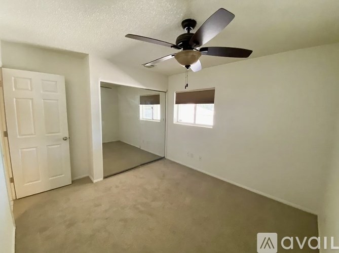 A room with a ceiling fan and two windows.