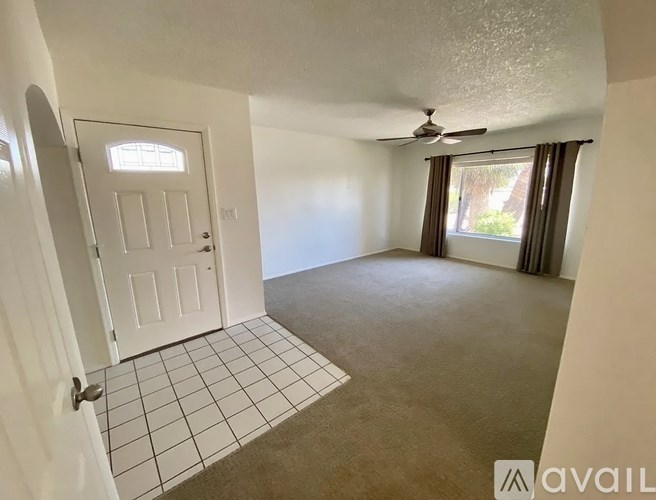 A room with a door, a fan, and a window with curtains.