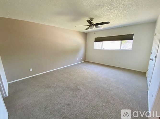 A room with a ceiling fan and a window with blinds.