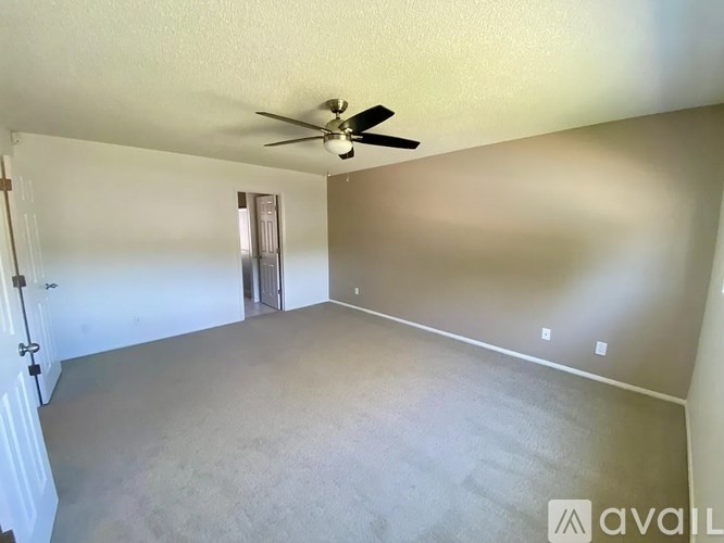 A spacious room with a ceiling fan and a door leading to another room.