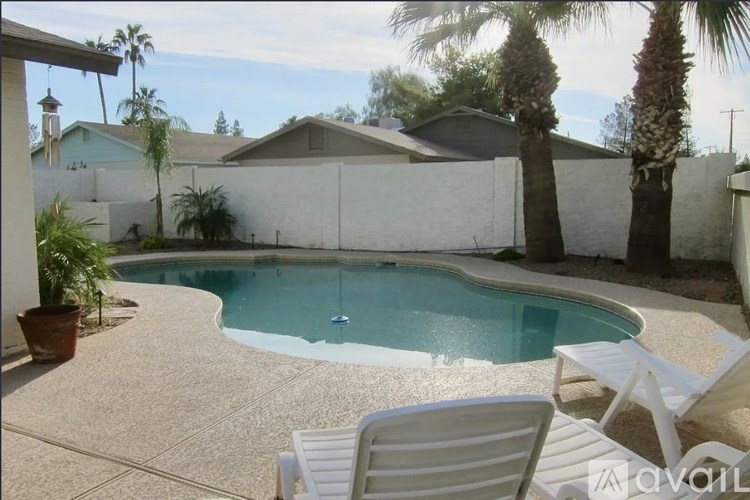 A pool surrounded by a white fence and palm trees.