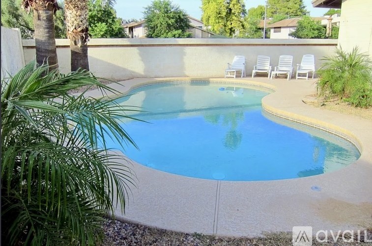 A small pool surrounded by a concrete wall and a few chairs.