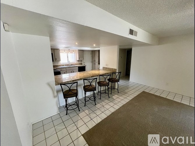 A kitchen with a table and chairs in the foreground and a hallway leading to another room in the background.