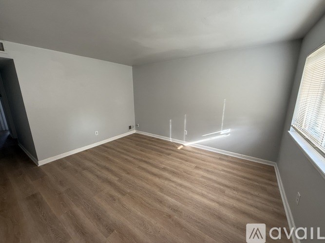 A room with wooden flooring and white walls is available for rent.
