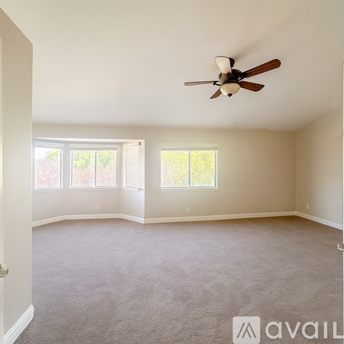 A spacious room with a ceiling fan and carpeted floor.
