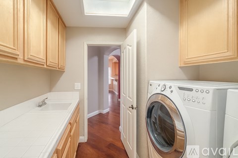 A washing machine is in the foreground of a kitchen.