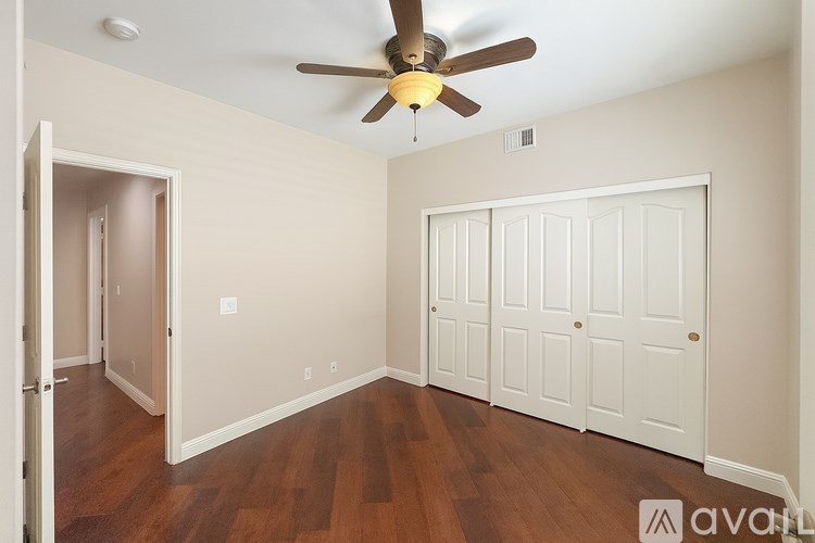 A room with a ceiling fan and wooden floors.