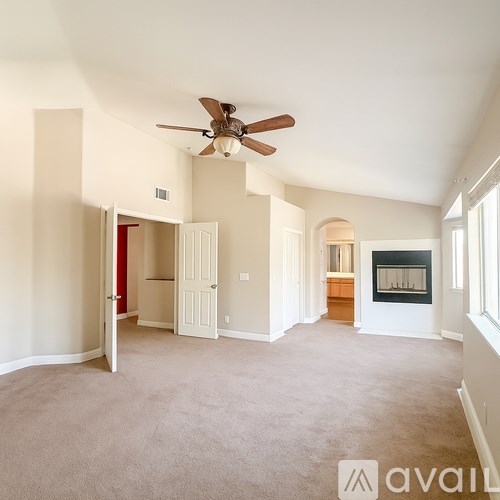 A spacious living room with a fireplace and a ceiling fan.