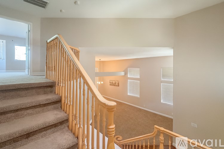 A staircase with a wooden banister and beige carpeted steps leads to a second floor.