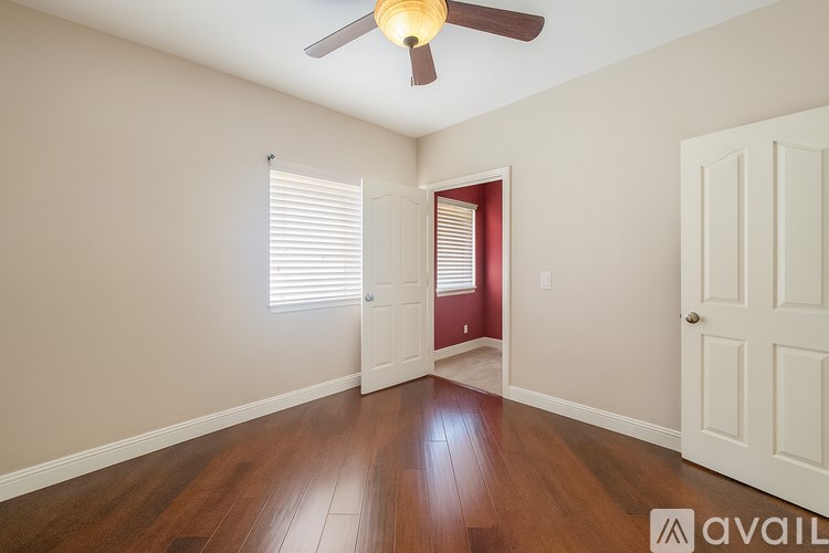 A room with a ceiling fan and wooden floors.