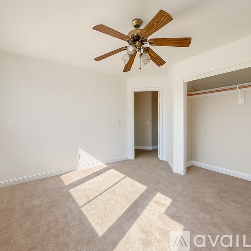 A room with a ceiling fan and carpeted floor.