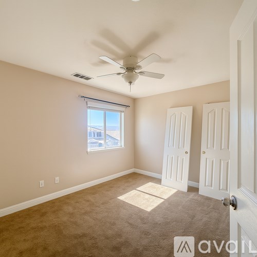 A room with a ceiling fan and a window with blinds.