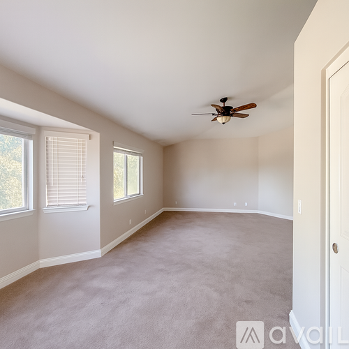 A spacious room with a ceiling fan and carpeted floor.