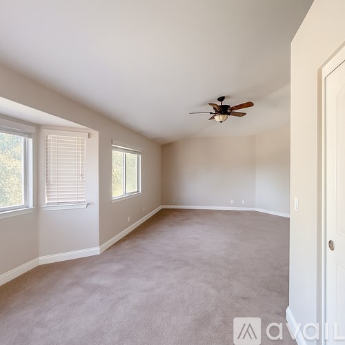 A spacious room with a ceiling fan and carpeted floor.