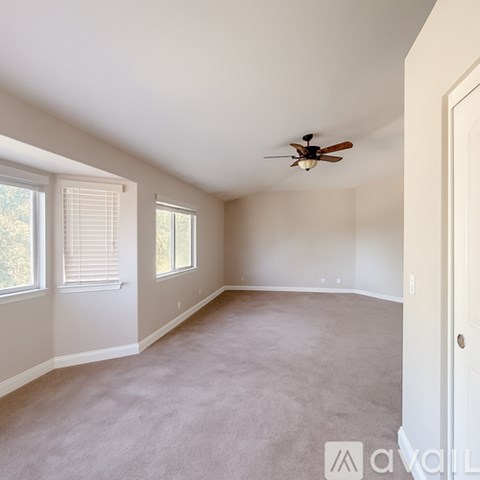 A spacious room with a ceiling fan and carpeted floor.