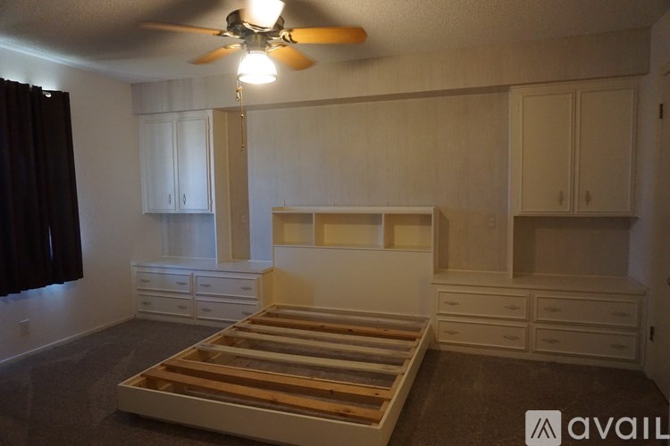 A room with a bed, drawers, and a ceiling fan.