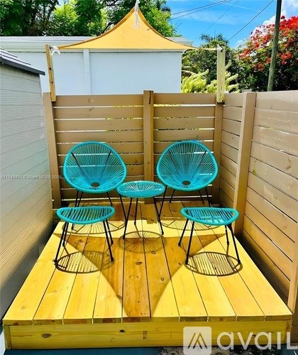 A set of four blue chairs are on a wooden deck.