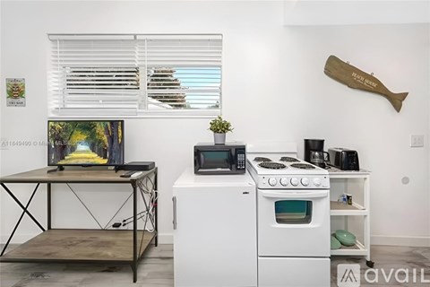 A kitchen with a white oven and microwave, a wooden table, and a painting on the wall.
