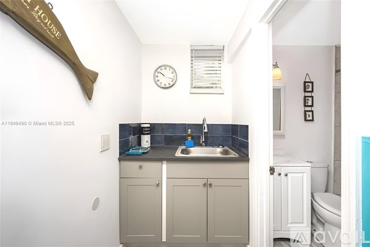 A small, white bathroom with a sink, toilet, and a clock on the wall.