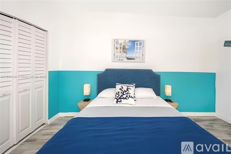 A bedroom with a bed, two lamps, and a painting on the wall.