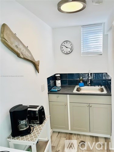 A kitchen with a sink, a toaster, and a clock on the wall.