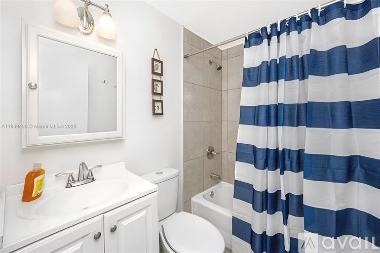 A bathroom with a white sink, toilet, and striped shower curtain.