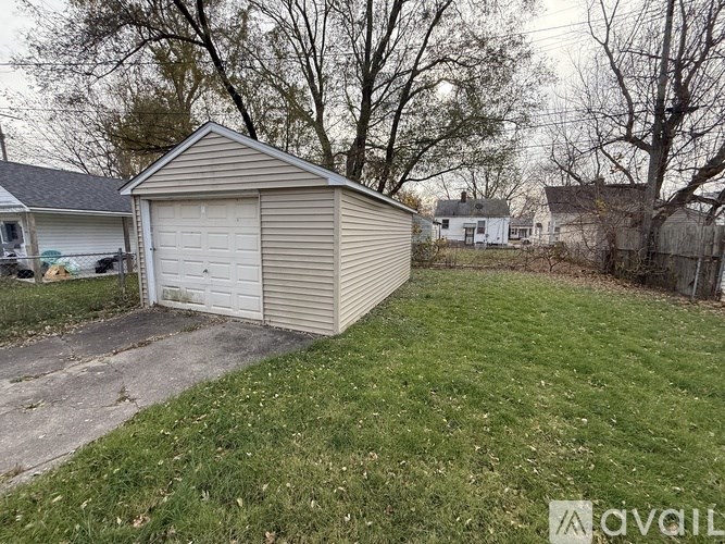 A detached garage is located in a grassy backyard.